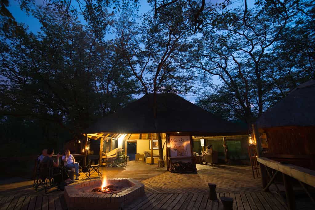 Open-air boma fire and thatched lounge behind