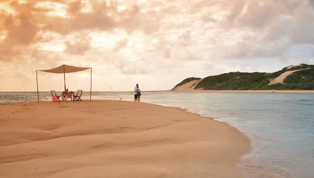 Couple on a romantic picnic on Inhaca Island are looking at the lodge.