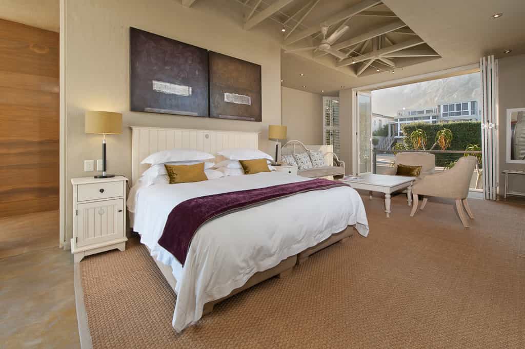 The bathroom door on the left with the King bed and seating area leading onto the mountain facing balcony of the Olive deluxe room