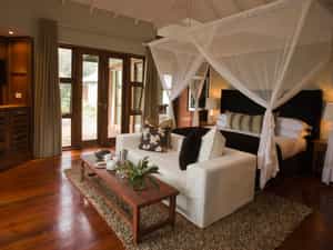 "The sleeping room is framed in glass doorways that lead to un outdoor deck."