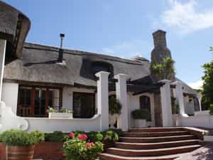 The characteristic front entrance of the main building of Whale Rock Luxury Lodge with the typical Hermanus style rock chimney.