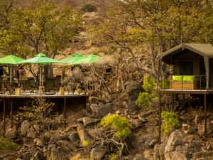 The main area deck and a room from across the dry riverbed, nestled in the Mopane grove.
