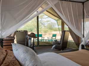 Netted porch and room with mosquito-netted beds, writing desk and private ensuite with bucket shower, flowing water to handbasin and flushing toilet