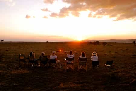 Guests watching the sun set from camp